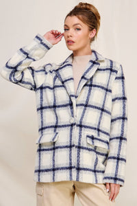 Woman wearing a blue and white checkered coat against a plain background