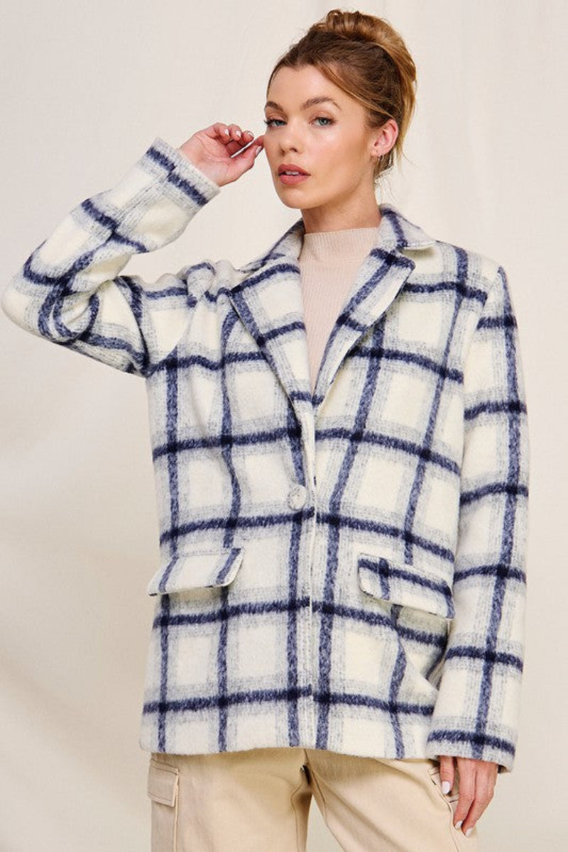 Woman wearing a blue and white checkered coat against a plain background