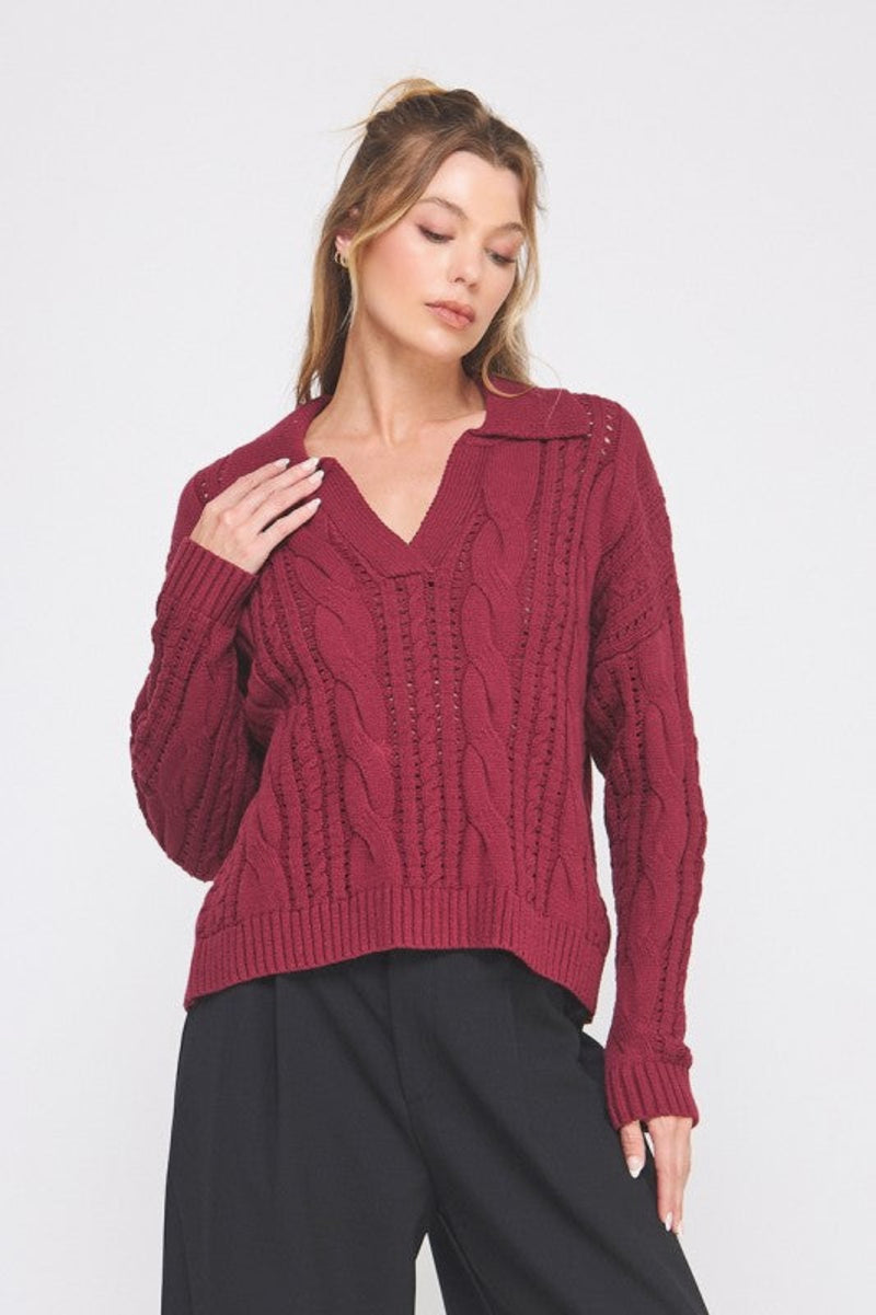 Woman wearing a burgundy cable knit sweater against a white background