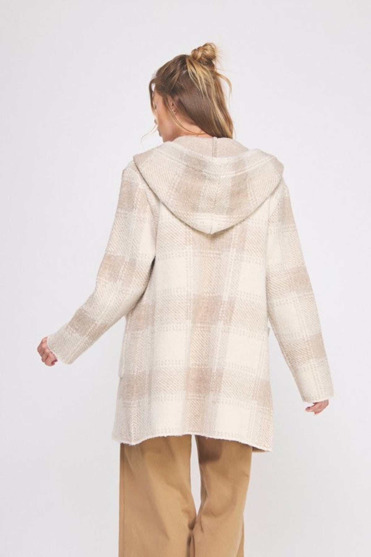 Person wearing a beige hooded coat on a white background