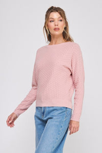 Woman wearing a pink sweater and blue jeans on a white background