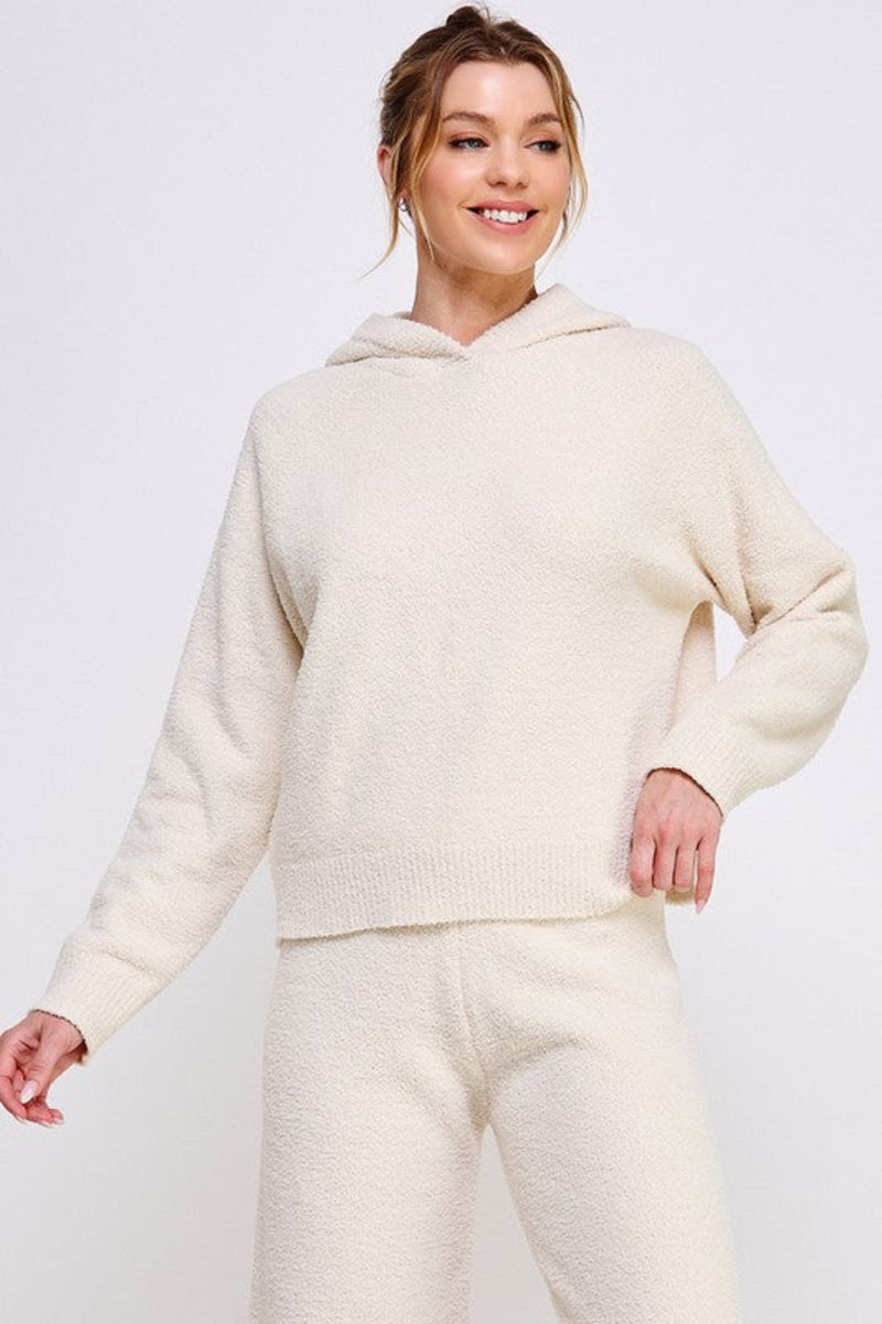 Woman wearing a cream-colored hoodie and pants on a white background