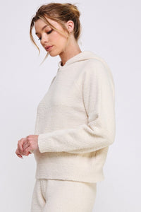 Woman wearing a cream-colored sweater against a white background
