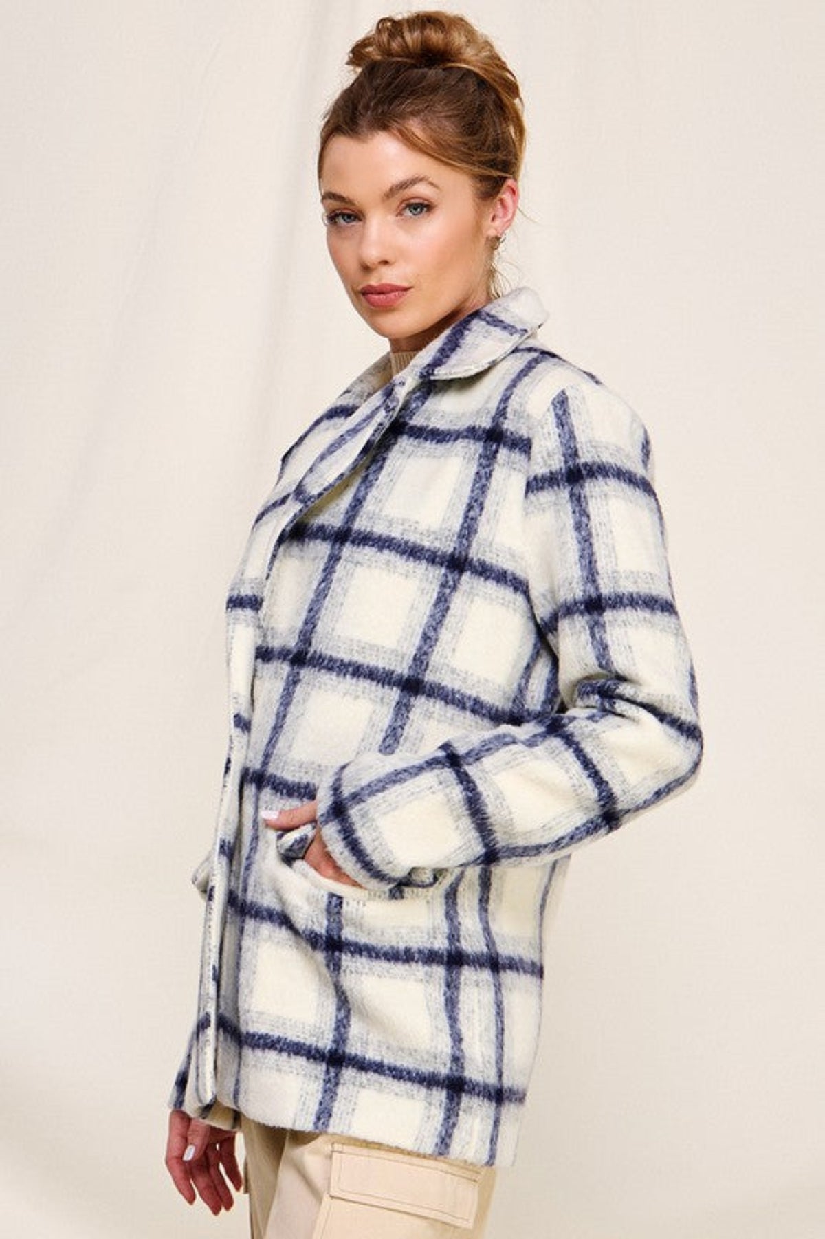 Woman wearing a checkered coat against a plain background