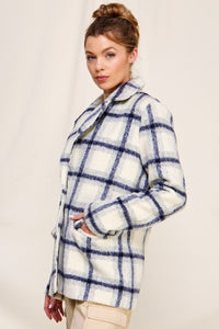 Woman wearing a checkered coat against a plain background