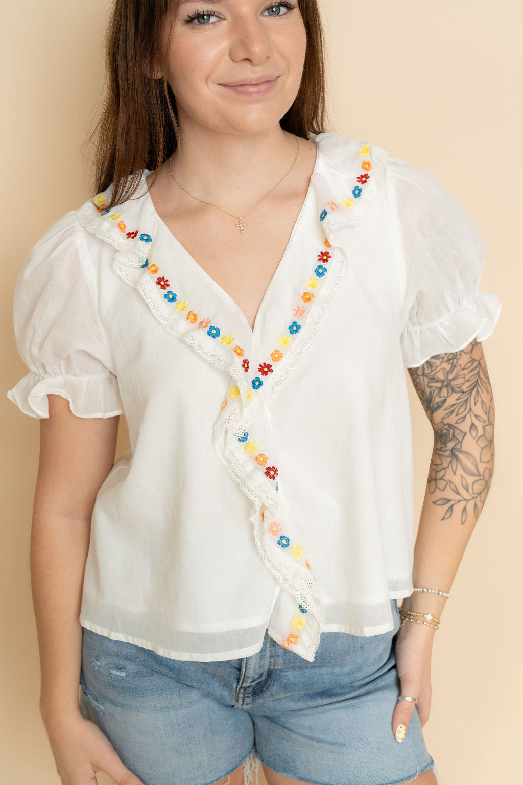 Women's white embroidered ruffle blouse paired with denim shorts a cute casual boho outfit