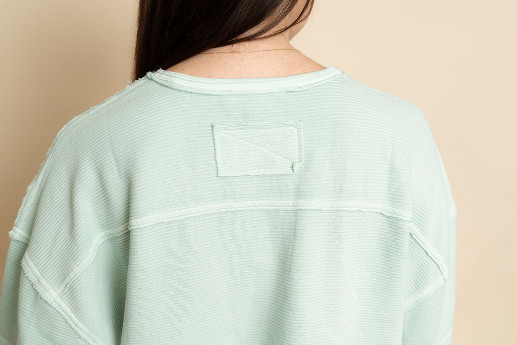 Closeup view of mint long sleeve top. 