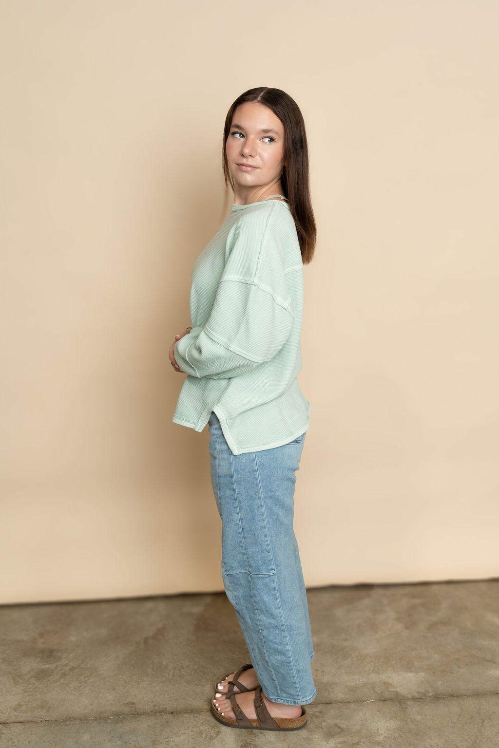 Side view of mint long sleeve top for women paired with light wash barrel jeans. 