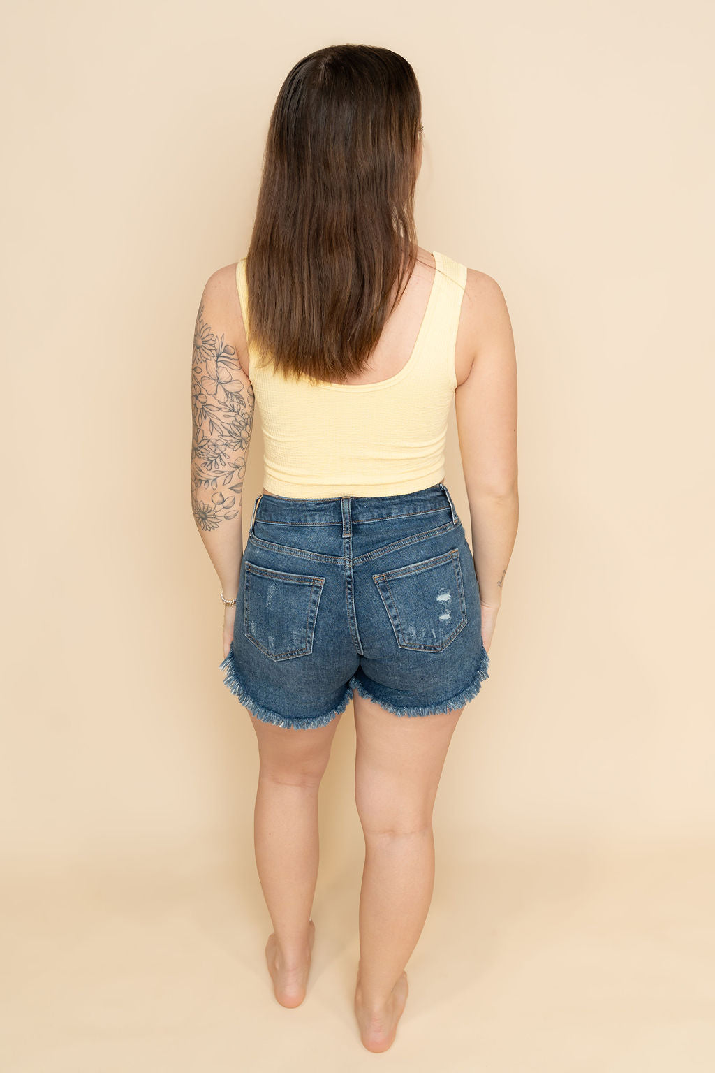 Back view of distressed dark wash denim shorts for women