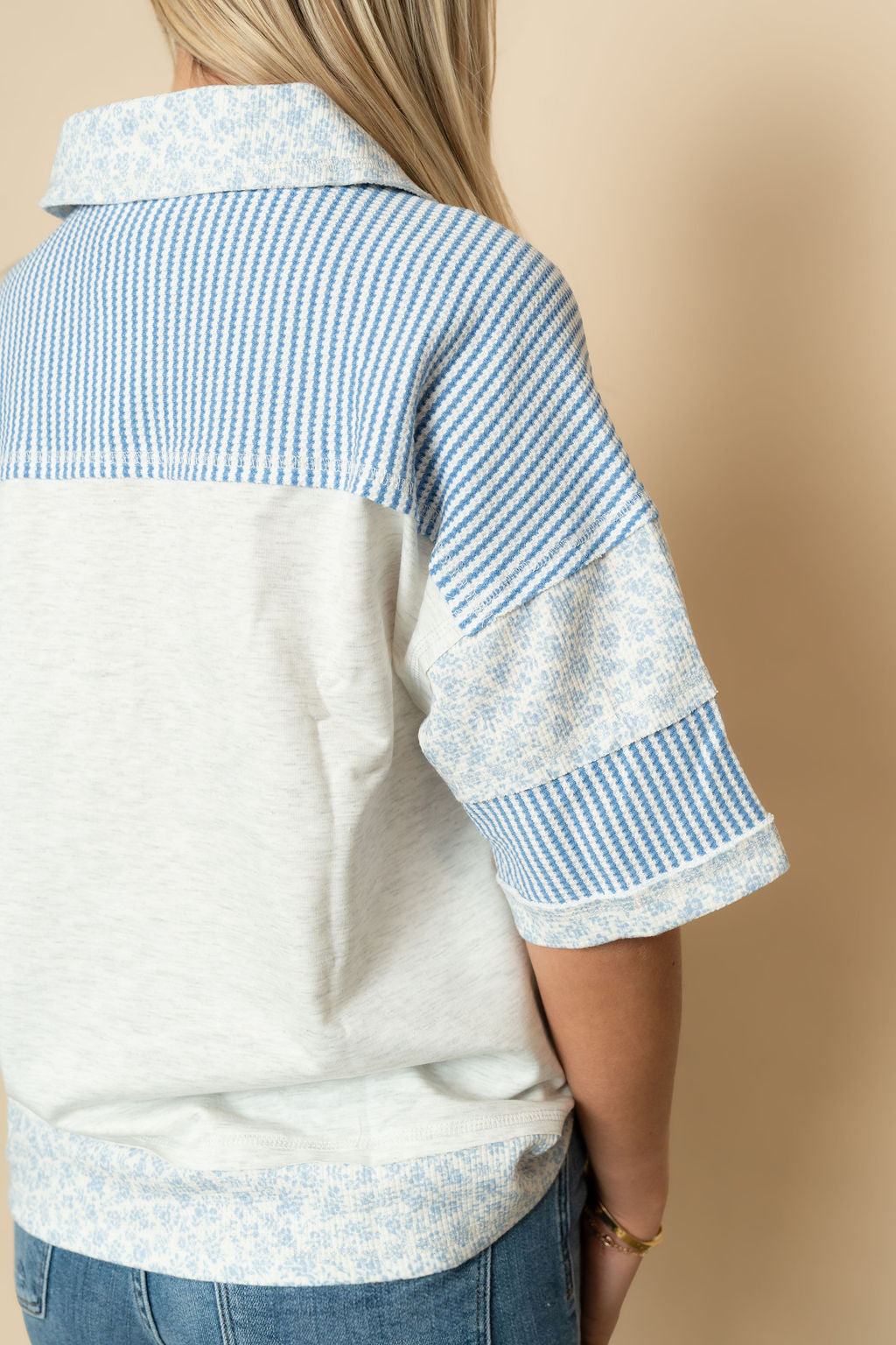 Back view of heather gray and blue floral short sleeve henley top. 