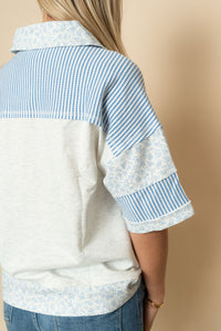 Back view of heather gray and blue floral short sleeve henley top. 