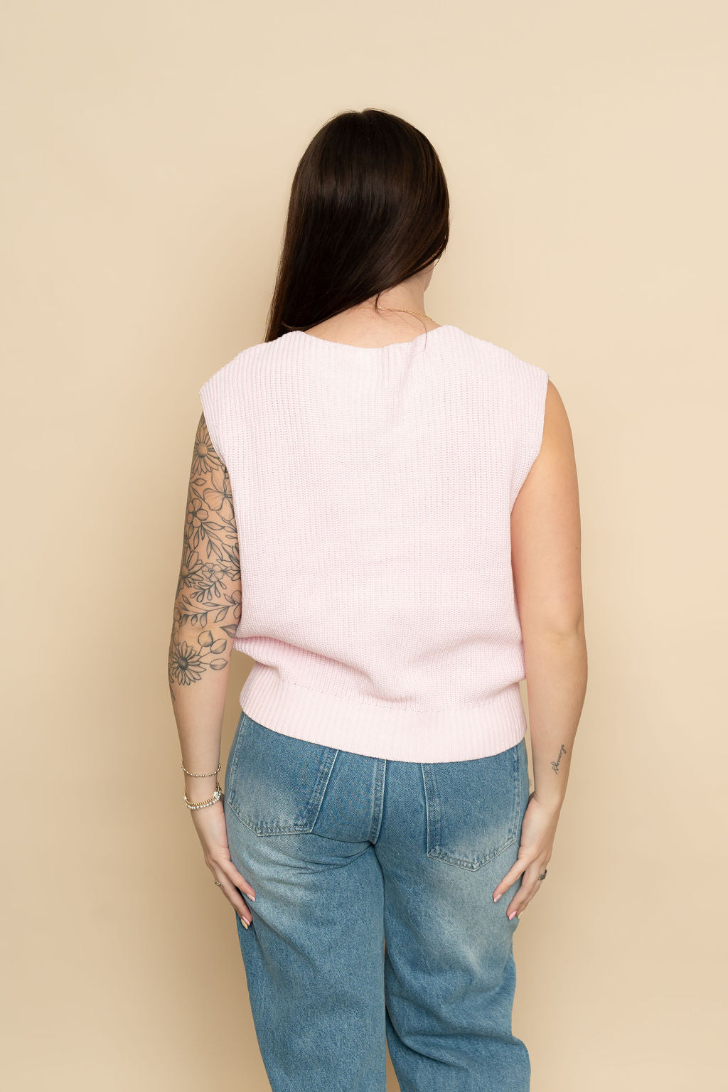 Back of pink sleeveless sweater vest styled for a casual everyday outfit. 