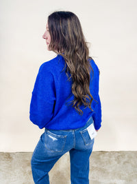 Model wearing a royal blue cardigan and dad jeans for a casual outfit. 