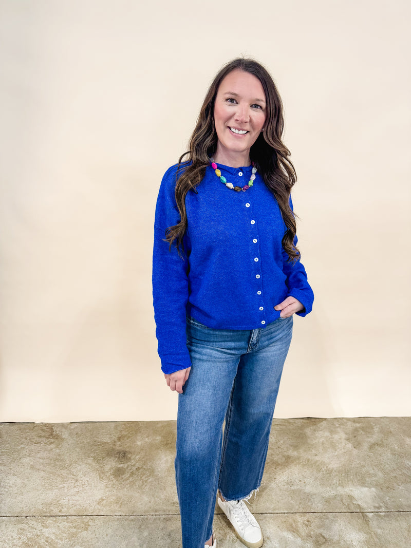 Woman wearing a royal blue cardigan and dad jeans.