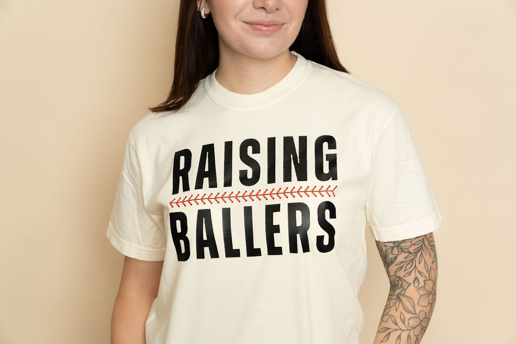 Ivory baseball graphic tee with Raising Ballers design, casual boutique -shirt for everyday style. 