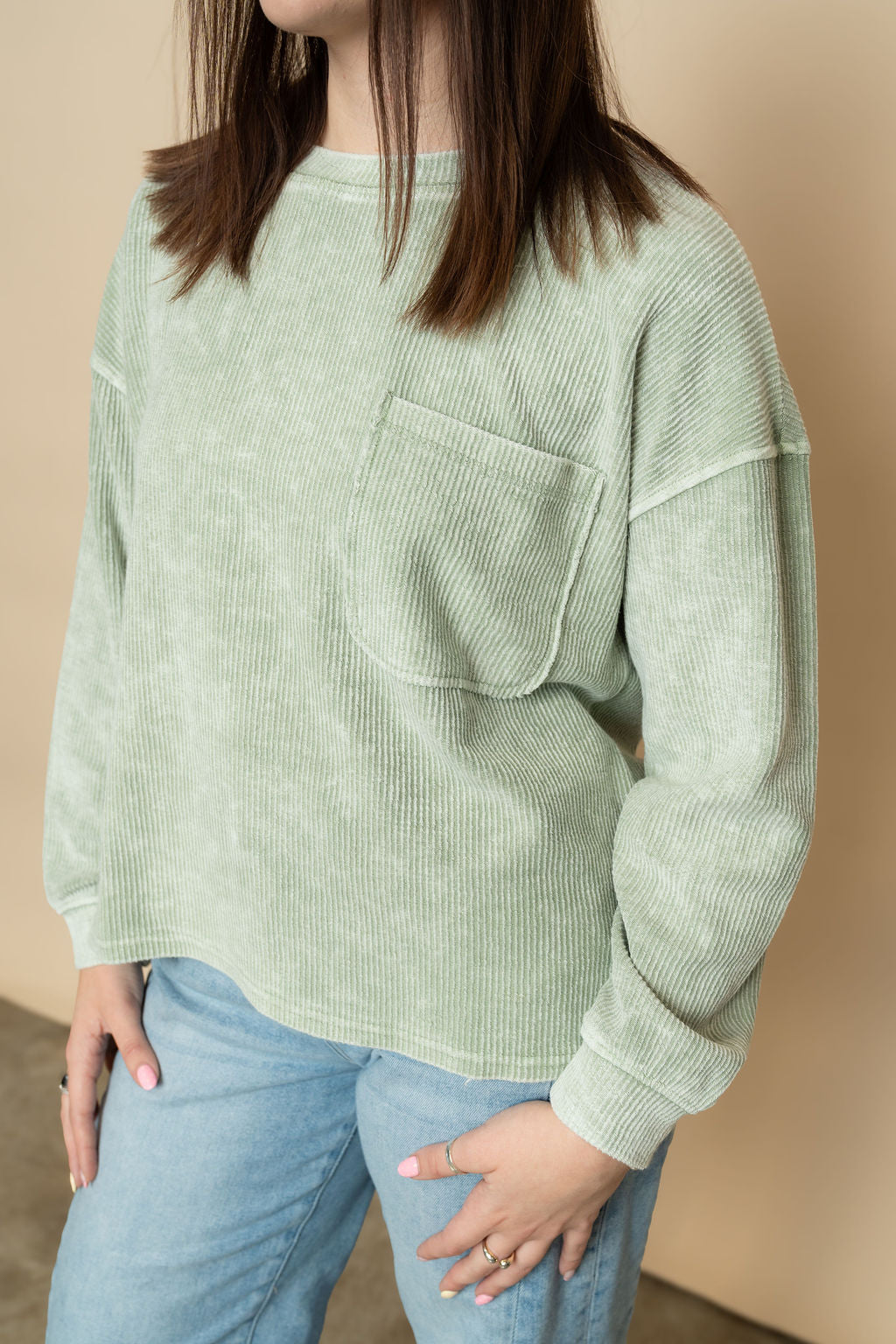 Closeup view of sage ribbed long sleeve basic top paired with light wash jeans for a cute casual outfit for women. 