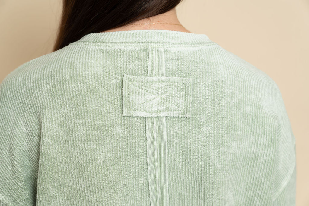 Closeup view of sage long sleeve top for women. 