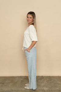 Side view of ivory knit short sleeve sweater paired with striped casual pants for a cute spring outfit. 