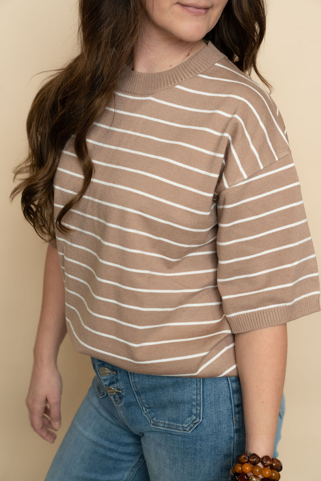 Closeup of brown and white short sleeve striped sweater top for women. 