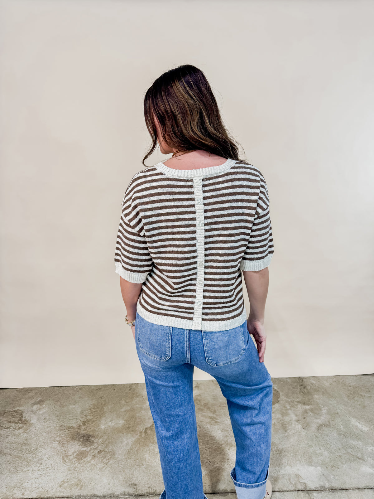 Back view of brown and cream short sleeve knit sweater with button details. 