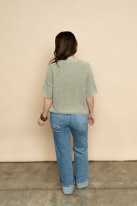 Back view of sage knit short sleeve sweater paired with light wash denim for a cute spring outfit for women. 