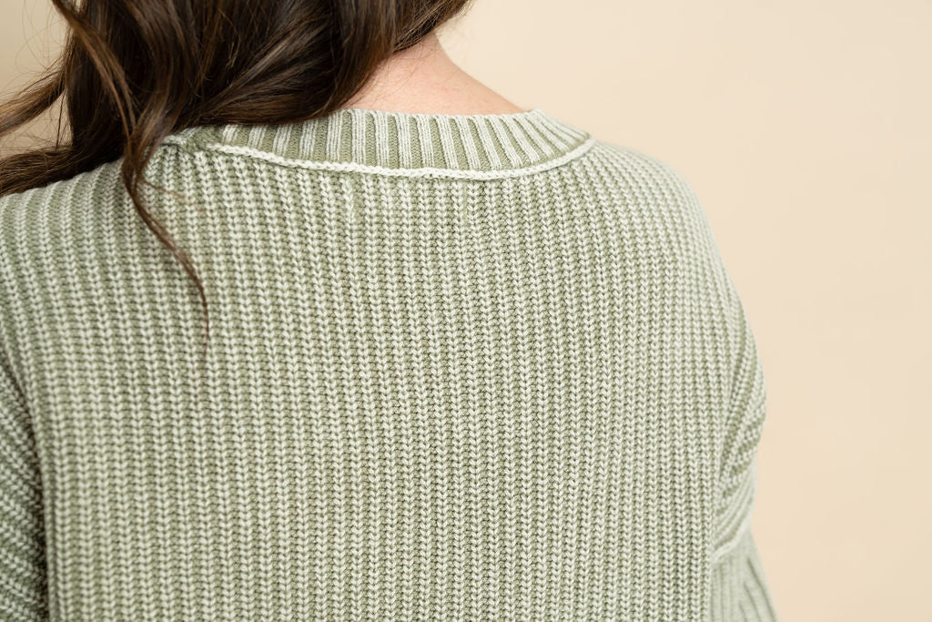 Closeup view of sage short sleeve knit sweater. 