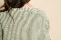 Closeup view of sage short sleeve knit sweater. 