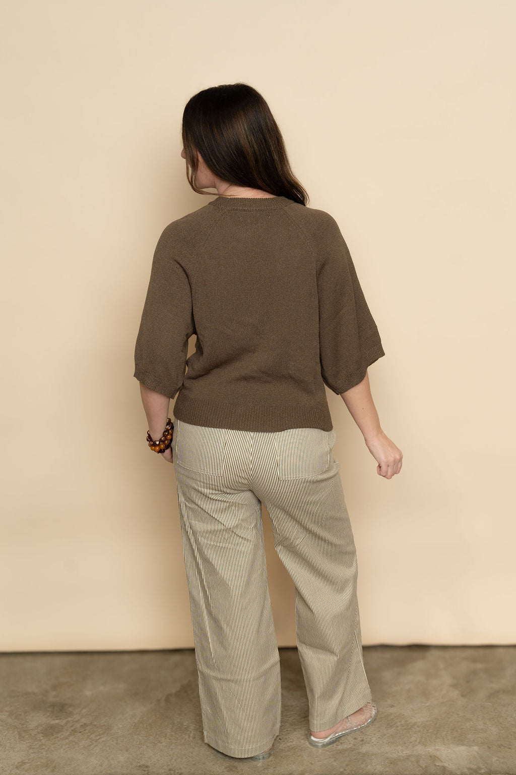 Back view of brown and white striped wide leg pants for women. 
