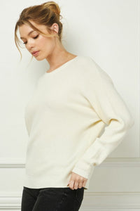 Woman wearing a white sweater against a light background