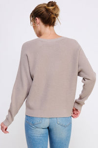Person wearing a beige sweater and blue jeans on a white background