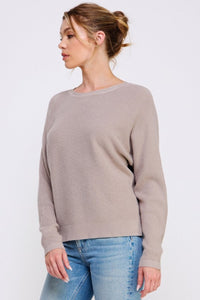 Woman wearing a beige sweater and blue jeans on a white background
