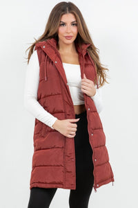 Woman wearing a red puffer vest over a white top and black pants on a white background