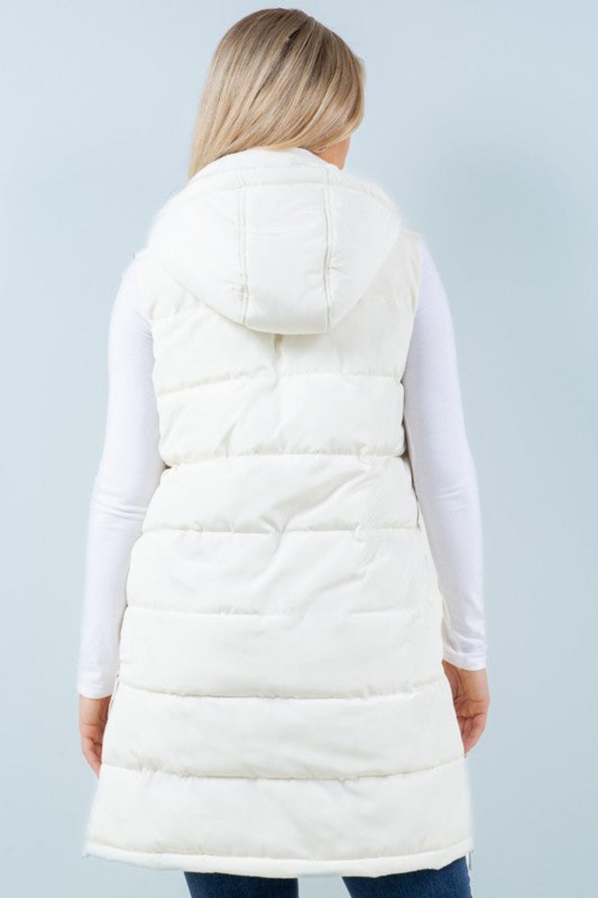 Woman wearing a white puffer vest on a light gray background